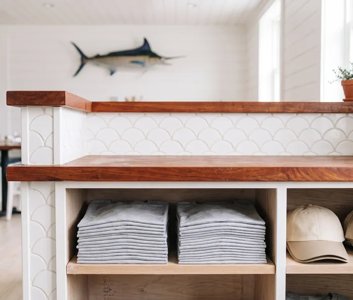 Folded tees in open cubbies built into the host stand of a coastal seafood restaurant.