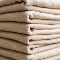 Folded edges of sand colored cotton jersey, close up.